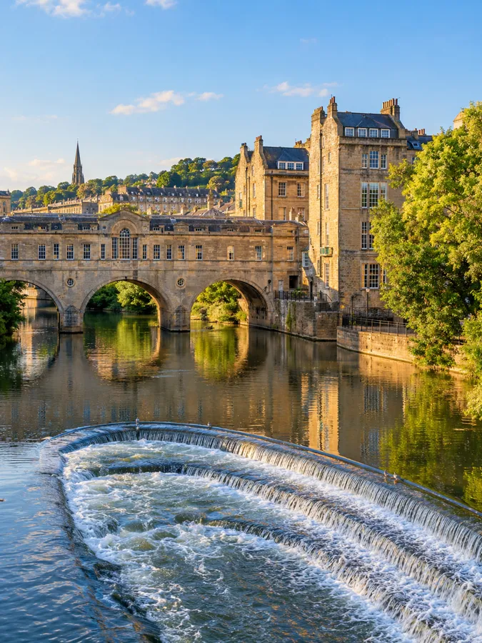 Pulteney Bridge und das Wehr am Fluss Avon in Bath bei warmem Sonnenschein